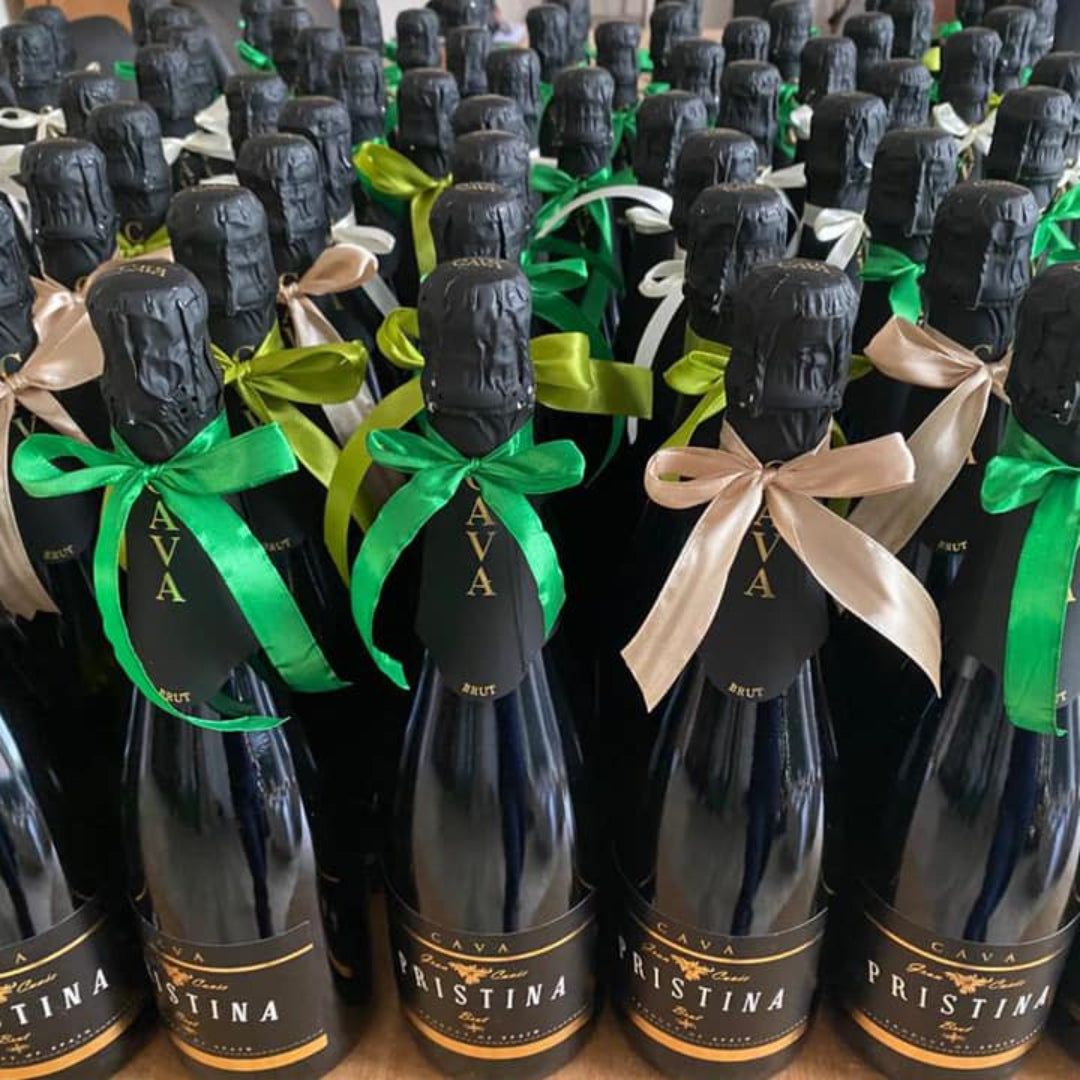 Bottles of Pristina wine with green and beige ribbons on a wooden surface