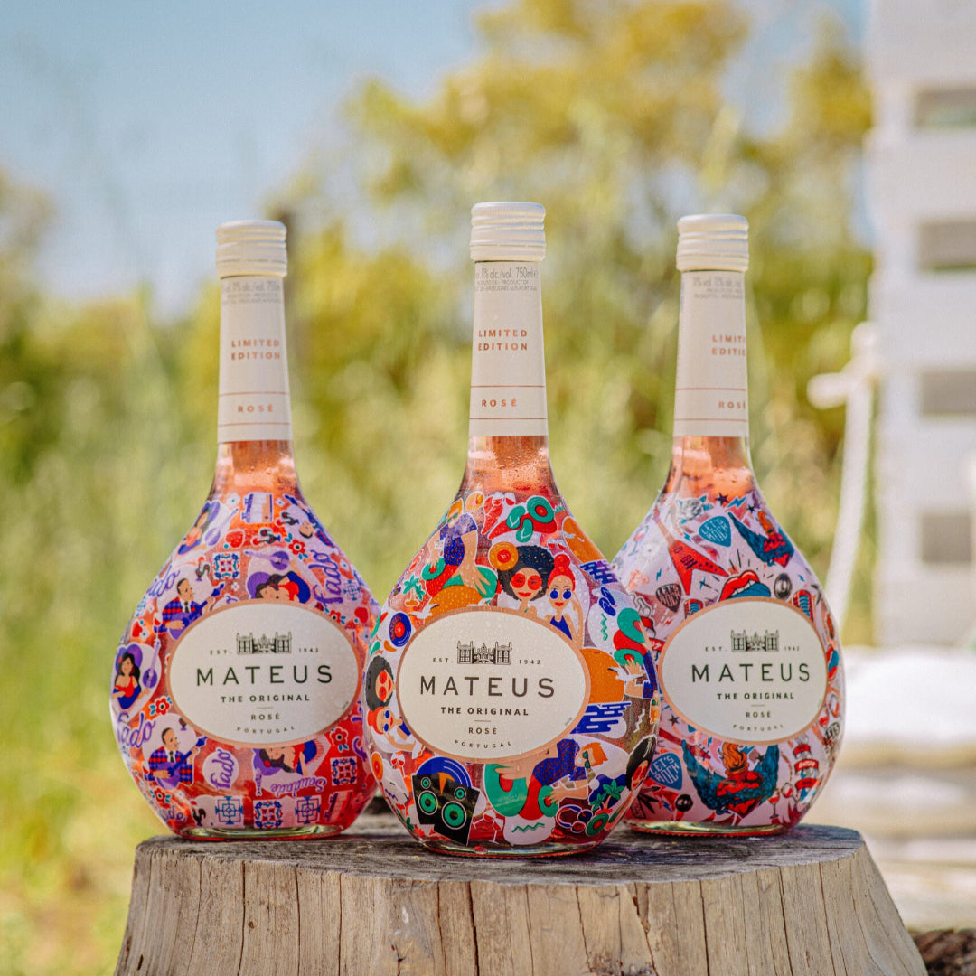 Three bottles of Mateus Rosé wine on a wooden stump with a blurred natural background