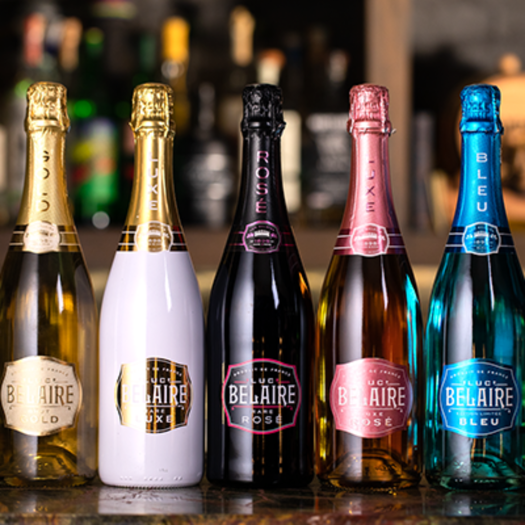 Five bottles of Belaire champagne on a bar counter with a blurred bar background.