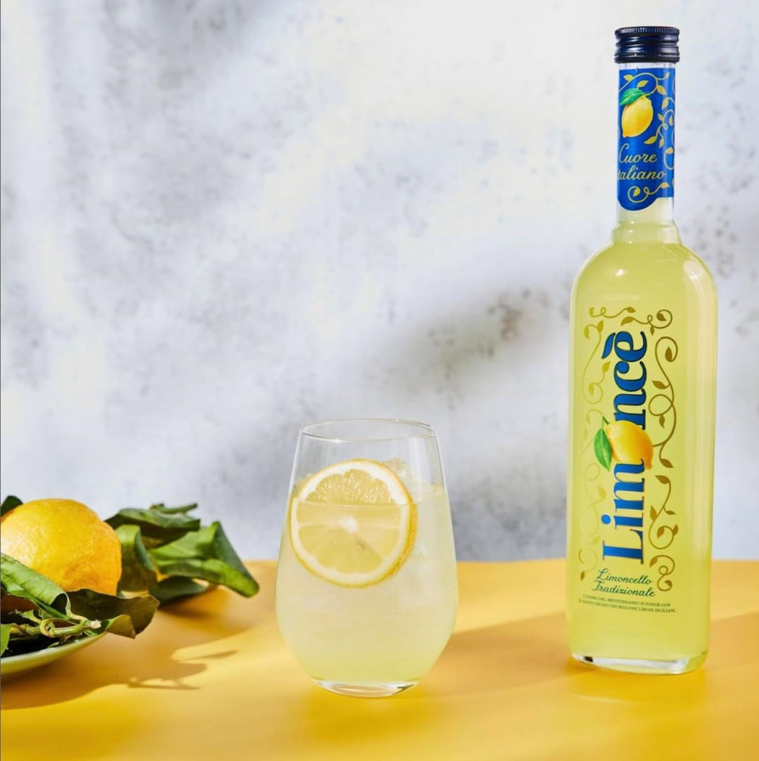 Bottle of Limoncello with a glass of lemonade on a yellow surface