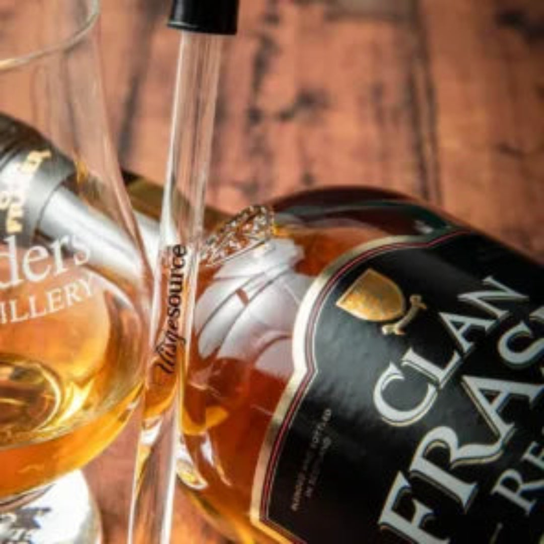 Whiskey glass and bottle with 'The Borders Distillery' branding on a wooden background