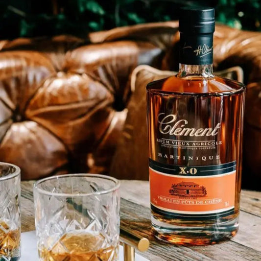 Bottle of Coèlément Martinique X.O. rum with two glasses on a wooden table.