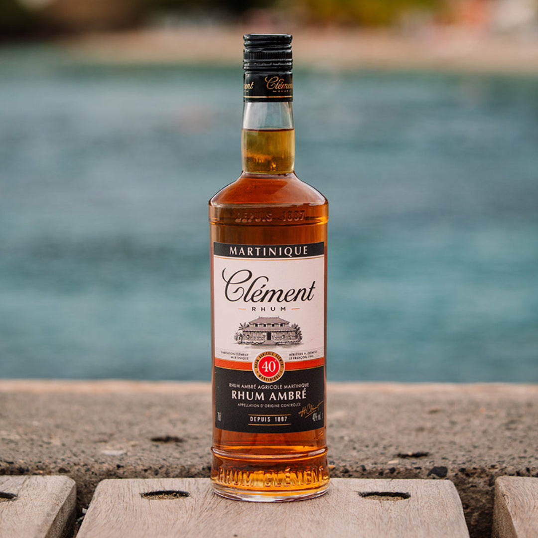 Bottle of Clément Rhum Ambre against a blurred natural background
