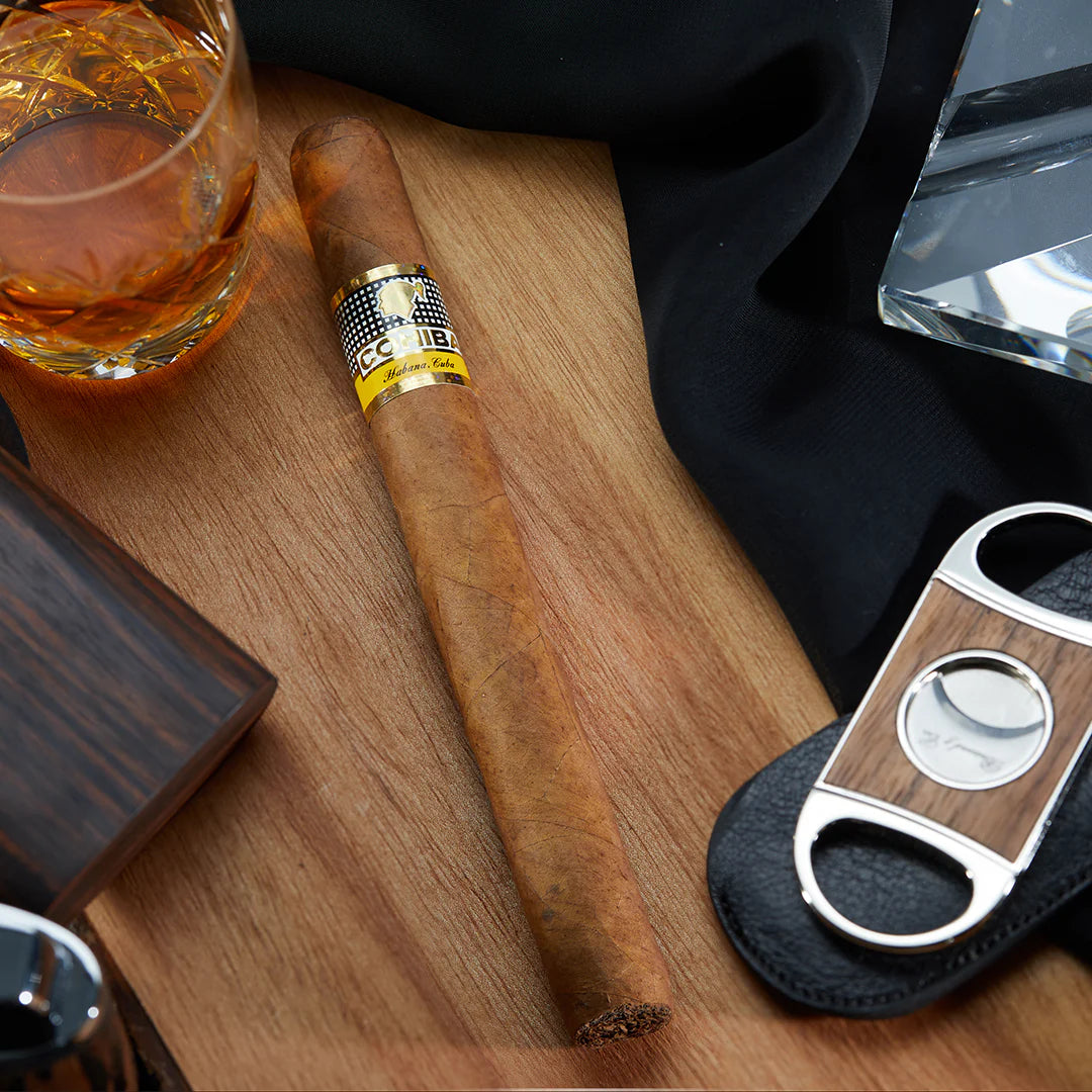 Cigar with a glass of whiskey and a cutter on a wooden surface