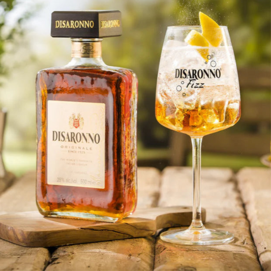Disaronno bottle and glass with lemon garnish on a wooden table outdoors