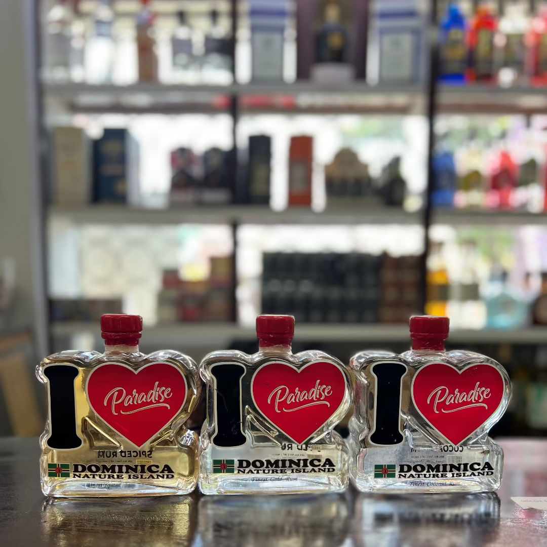 Three miniature bottles of 'I Love Paradise' rum on a bar counter with shelves in the background.