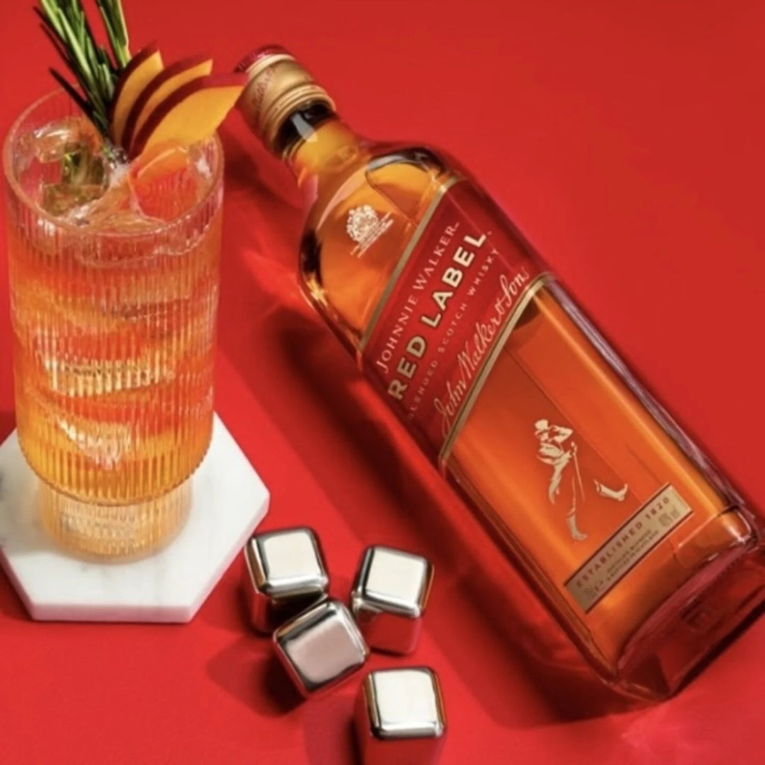 Johnnie Walker Red Label bottle with cocktail and ice cubes on a red background