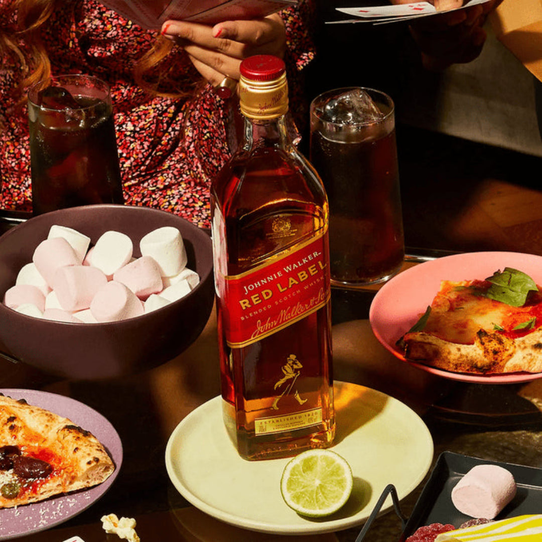 Johnnie Walker Red Label whisky bottle on a table with food and drinks