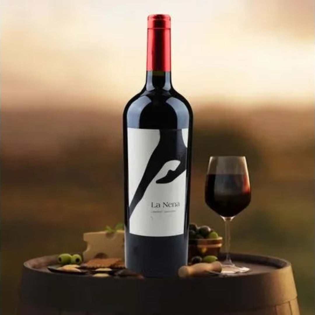 Red wine bottle with a glass on a wooden barrel against a blurred background