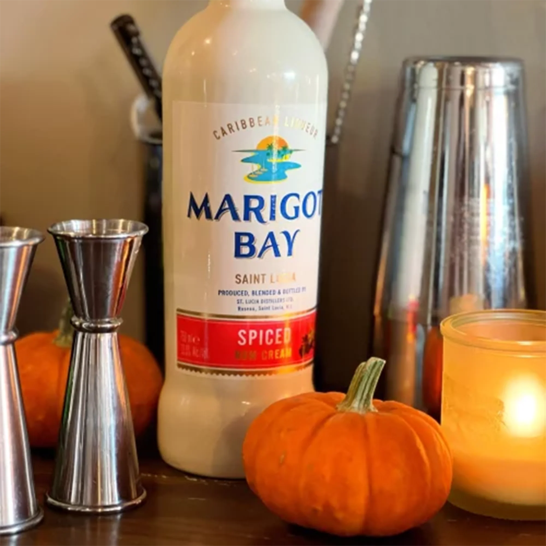 Marigot Bay spiced rum bottle with cocktail shakers and pumpkins on a bar counter.