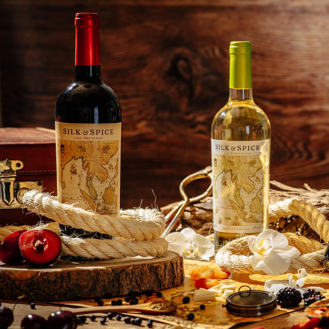 Four bottles of Silk & Spice wine on a rustic wooden table with various spices and ingredients.