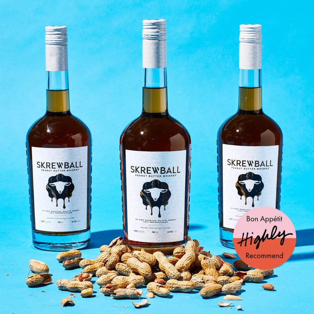 Three bottles of Skrewball Whiskey with peanuts on a blue background