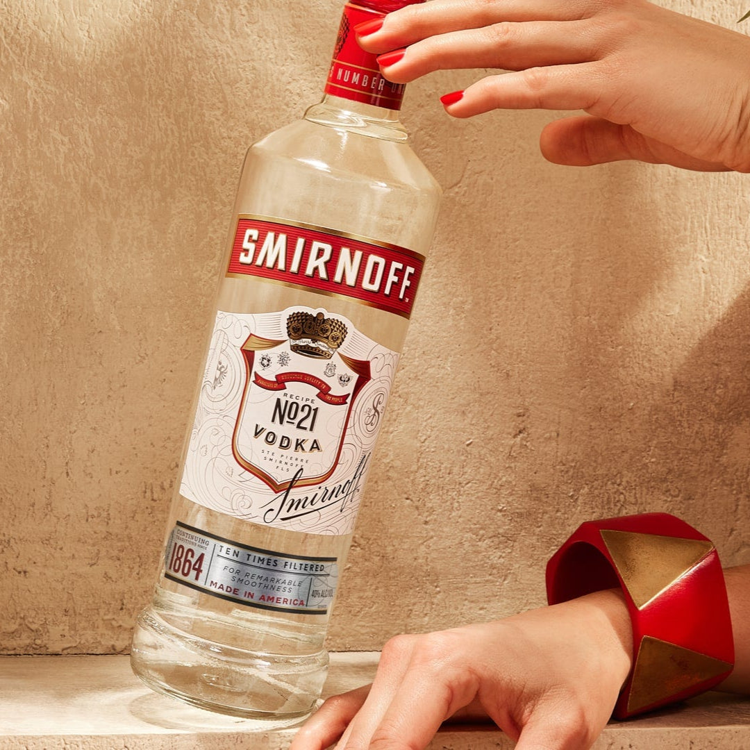 Person in red outfit with a bottle of Smirnoff Vodka on a textured surface