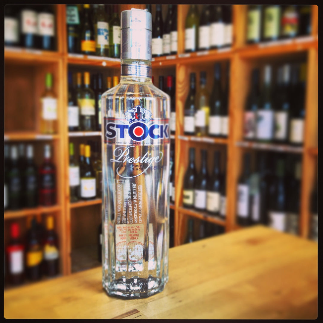 Bottle of Stock vodka on a wooden surface with shelves of bottles in the background
