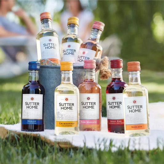 Assorted Sutter Home wine bottles on a wooden block outdoors.