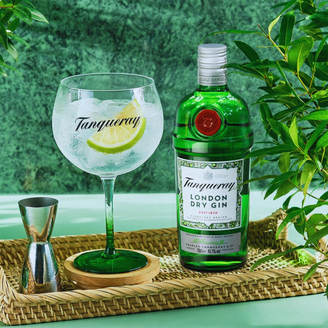 Tanqueray London Dry Gin bottle with a glass and lemon wedge on a tray with a green background