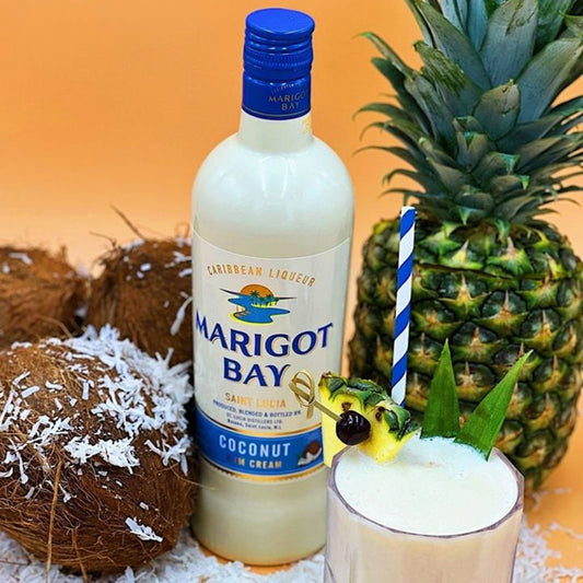 Marigot Bay coconut cream liqueur bottle with a cocktail and pineapple on a decorative surface.